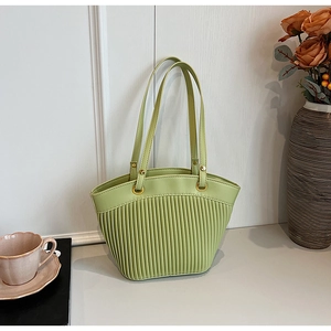 Detail of light green tote bag with vertical pleated texture and gold ring accents