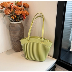 Detail of avocado green pleated straw tote bag with gold rings and orange flowers