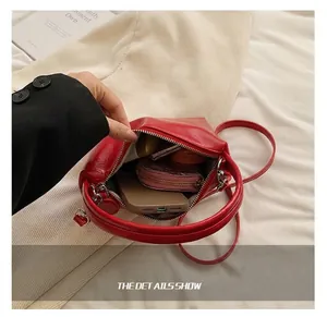 Internal capacity of a red glossy leather handbag with phone and wallet stored inside