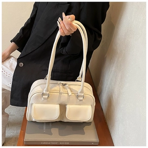 Close-up of a white textured faux leather Boston bag with two front flap pockets and straps