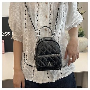 Close-up of black quilted mini backpack with silver turn-lock and woven chain strap