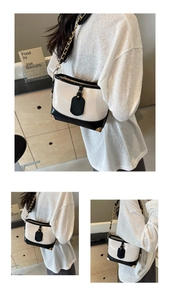 Detail view of contrast bucket bag with gold chain strap and metal corner protectors