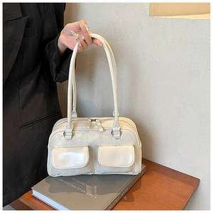 Detail of cream glossy shoulder bag with dual front pockets and double zipper closure