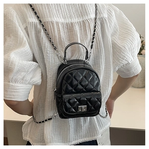Close-up of black quilted leather mini backpack with metal chain straps and twist lock