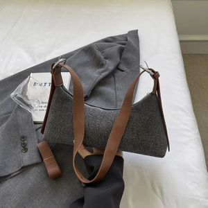 Grey fabric underarm bag with brown leather straps displayed on a blazer