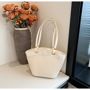 Detail of white pleated tote bag with sleek faux leather texture and gold ring hardware