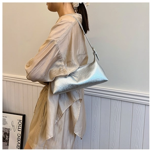 Silver metallic baguette shoulder bag with crinkled texture worn on model's shoulder