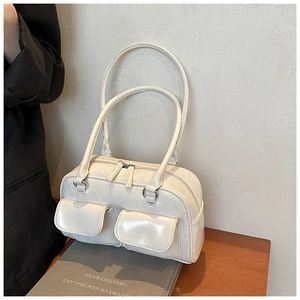 Detail of cream white shoulder bag featuring double front flap pockets and silver hardware