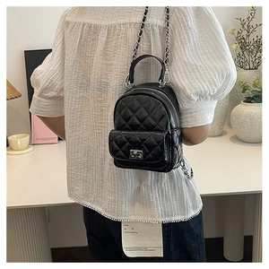 Detail of a quilted mini backpack with silver chain straps and a turn-lock closure