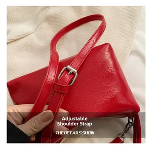 Detail of adjustable red leather shoulder strap with silver metal buckle on pleated bag