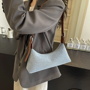 Blue denim hobo bag with brown leather strap and silver zipper in retro style