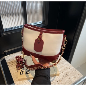Detailed shot of red and white bucket bag featuring golden chain and metal corner accents