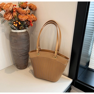 Detail of pleated faux leather tote bag with golden metal rings and brown finish