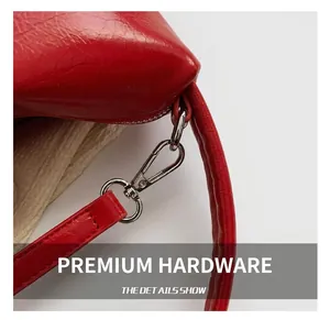 Detailed close-up of silver metal hook and red glossy leather strap on a small handbag