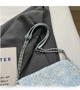 Detail of light blue woven tote bag with silver chain strap and modern texture
