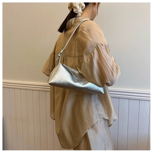Silver metallic shoulder bag featuring pleated texture and knot strap on model