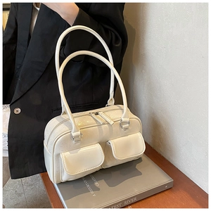 Detail of a creamy white leather bowling bag with dual front pockets and shoulder straps