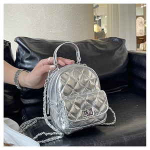 Detail of silver quilted mini backpack featuring metallic chain strap and metal lock