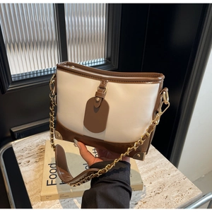 Close-up of contrast bucket bag with gold corner guards and metal chain strap detail