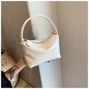 Detail showing the pleated texture and round handle of this white minimalist handbag