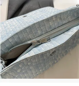 Close-up of silver metal zipper and woven leather texture on light blue tote bag