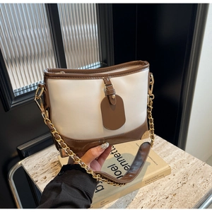 Detail of contrast bucket bag with white leather body and gold chain strap