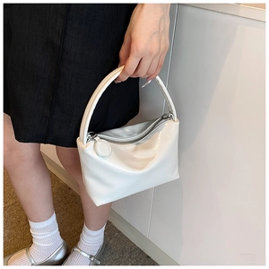 Close-up of white glossy pleated leather handbag with round metal zipper puller detail