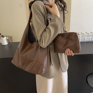 Vintage brown oil wax leather tote bag and clutch set worn by model in a cafe setting