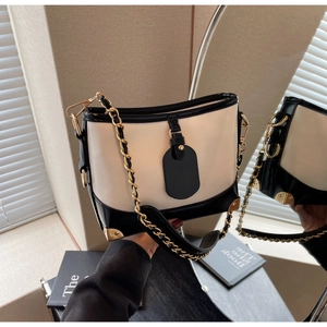 Detail of contrast bucket bag with retro metal corner protectors and thick chain strap