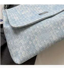 Detail of light blue woven texture tote bag featuring silver metal lock and chain strap