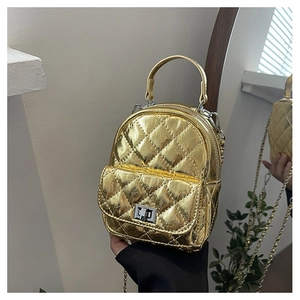 Close-up of golden quilted mini backpack featuring a metallic top handle and chain strap