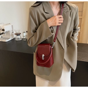 Détail du mini sac bandoulière en cuir verni bordeaux avec fermoir argenté et bandoulière fine