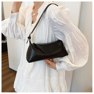Close-up of black pleated leather underarm bag featuring silver zipper and slim strap