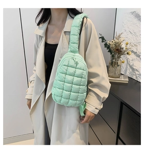 Close-up of mint green quilted nylon shoulder bag with wide padded strap on a model