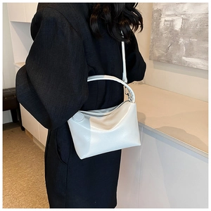 Modern white glossy faux leather shoulder bag shown on a model with minimalist outfit