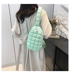 Detail of mint green quilted nylon crossbody bag with dual silver zippers and wide strap