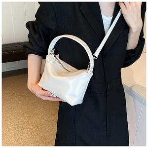 Detail shot of the white semi-circle leather handbag featuring a smooth zipper closure