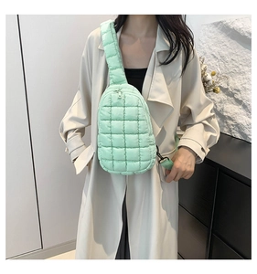 Detail of mint green quilted nylon sling bag with puffy texture and adjustable wide strap