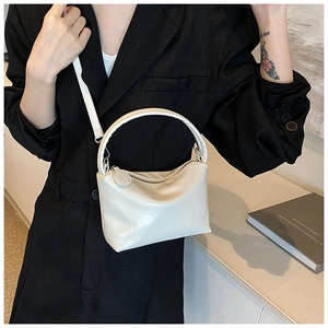 Detail of a minimalist cream white pebble grain leather handbag with round top handles