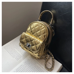 Detail of golden quilted mini backpack with metal chain strap on vintage book background