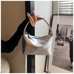 Close-up of silver metallic handbag with crinkled texture and curved handle detail
