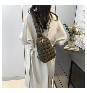 Detailed view of the quilted brown nylon chest bag worn on a person's back