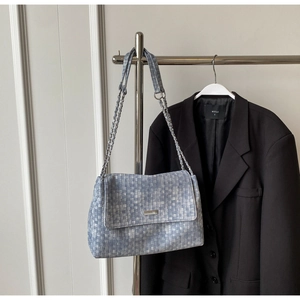 Detail of light blue woven tote bag with silver chain strap and metal buckle closure