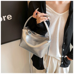 Detail shot of silver metallic pleated handbag featuring a top handle and shoulder strap