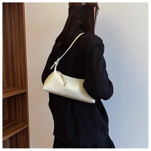 Detail view of cream faux leather baguette bag with silver buckle and shoulder strap