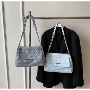 Close-up of chain straps and metal buckles on tweed shoulder bags in blue