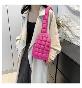 Detail of bright pink quilted nylon crossbody bag with padded straps and soft texture
