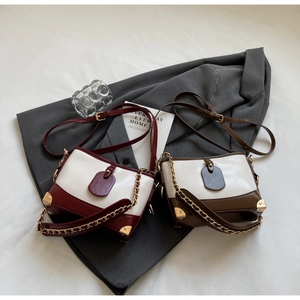 Close-up of contrast bucket bag with glossy leather texture and gold chain straps