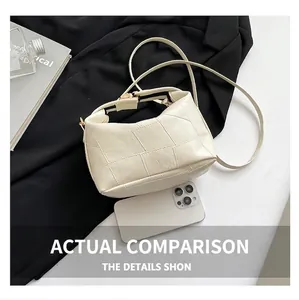 Sac seau blanc à texture carrée et boucle dorée présenté à côté d'un smartphone