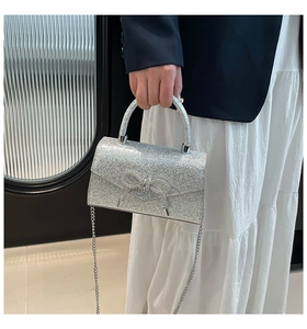 Close-up of silver sequined handbag with a bow detail and metallic chain strap